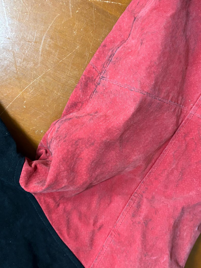 Puede incluir: Primer plano de una prenda roja y negra. La secci&oacute;n roja tiene un aspecto texturizado y descolorido con costuras visibles. La secci&oacute;n negra es lisa y contrasta con el rojo. La prenda parece estar hecha de un material suave.