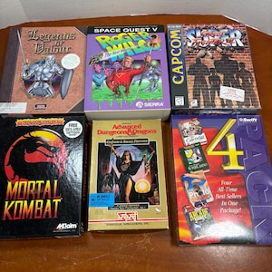 Puede incluir: Seis cajas de juegos de PC antiguos dispuestas en dos filas. Los títulos incluyen Legends of Valour, Space Quest V, Super Street Fighter II, Mortal Kombat, Advanced Dungeons & Dragons Gateway to the Savage Frontier y un paquete de 4.