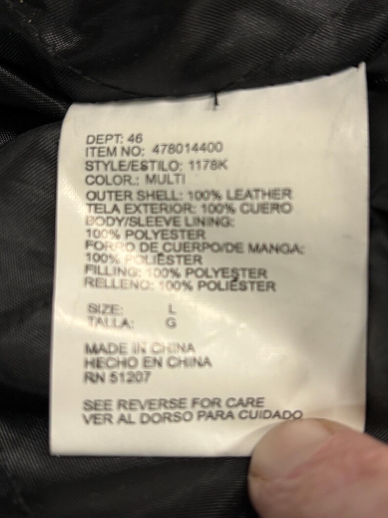 Puede incluir: Primer plano de una etiqueta blanca con texto negro. La etiqueta enumera el departamento, el n&uacute;mero de art&iacute;culo, el estilo y el color como multi. Tambi&eacute;n enumera los materiales: 100% cuero, forro y relleno de poli&eacute;ster. Talla L.