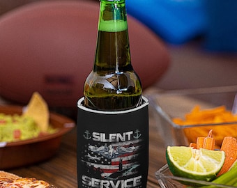 May include: A green glass beer bottle in a black can cooler. The cooler features the text "SILENT SERVICE" with an American flag and nautical imagery. The background includes snacks and a football.