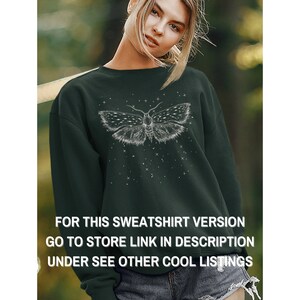 May include: A dark green sweatshirt with a white moth graphic and a starry design. The text "FOR THIS SWEATSHIRT VERSION GO TO STORE LINK IN DESCRIPTION UNDER SEE OTHER COOL LISTINGS" is printed on the bottom of the sweatshirt.