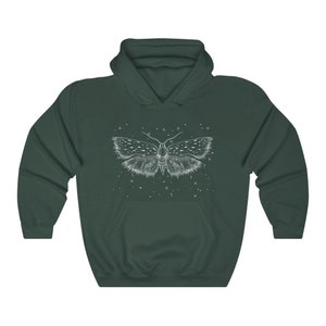 May include: A dark green hoodie with a white outline of a moth with wings spread wide. The moth is surrounded by small white dots, resembling stars.