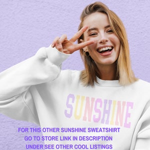 Peut inclure: Un sweat-shirt blanc avec le mot "SUNSHINE" imprim&eacute; en couleurs arc-en-ciel. Le texte "FOR THIS OTHER SUNSHINE SWEATSHIRT GO TO STORE LINK IN DESCRIPTION UNDER SEE OTHER COOL LISTINGS" est imprim&eacute; sous le mot "SUNSHINE".