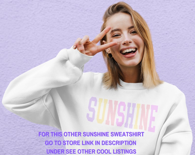 Peut inclure: Un sweat-shirt blanc avec le mot "SUNSHINE" imprim&eacute; en couleurs arc-en-ciel. Le texte "FOR THIS OTHER SUNSHINE SWEATSHIRT GO TO STORE LINK IN DESCRIPTION UNDER SEE OTHER COOL LISTINGS" est imprim&eacute; sous le mot "SUNSHINE".