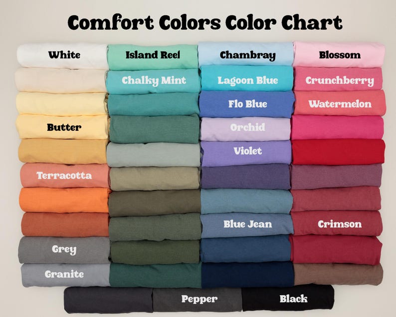 K&ouml;nnte beinhalten: Eine Farbkarte mit Stoffmustern von Comfort Colors. Die Karte enth&auml;lt Farben wie Wei&szlig;, Island Reel, Chambray und Blossom. Jede Farbe ist mit ihrem Namen in wei&szlig;em Text beschriftet.
