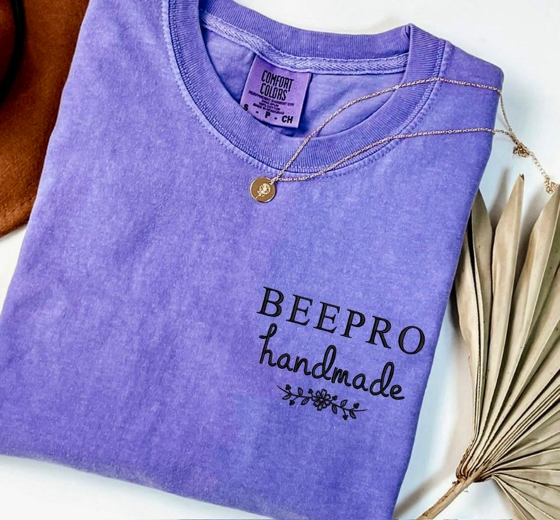 May include: Purple t-shirt with the text "BEEPPRO handmade" in black lettering with a small floral design underneath.