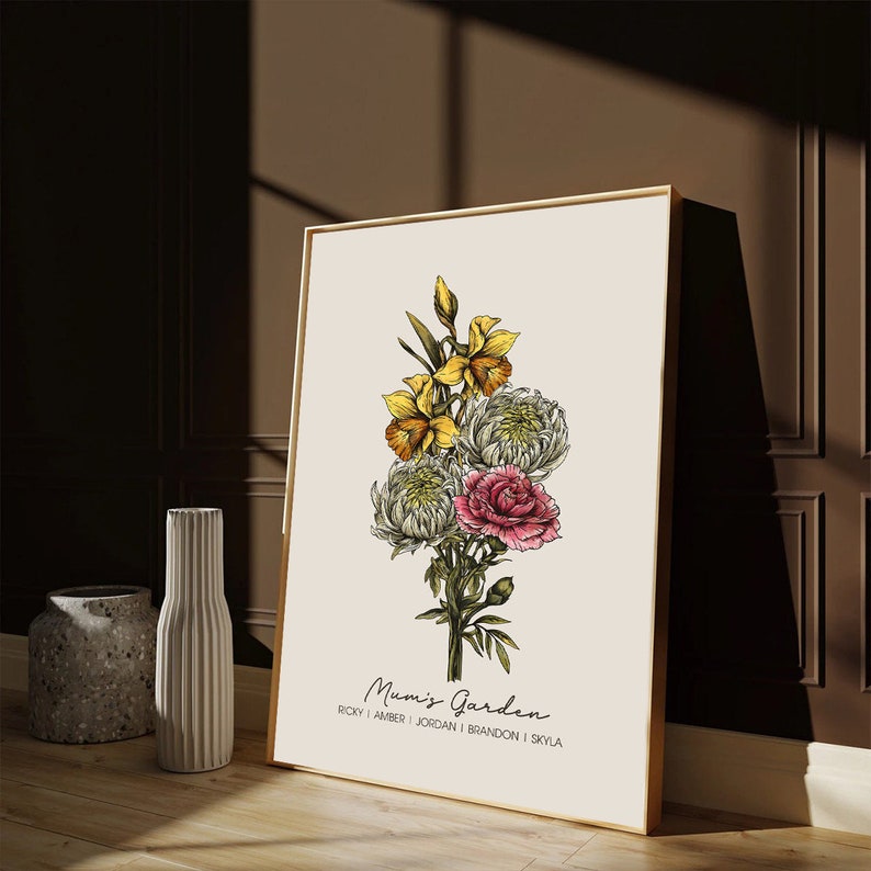 May include: A framed print featuring a floral bouquet of yellow daffodils, white chrysanthemums, and pink carnations. The print is titled "Mum's Garden" and includes the names "Ricky, Amber, Jordan, Brandon, and Skyla".