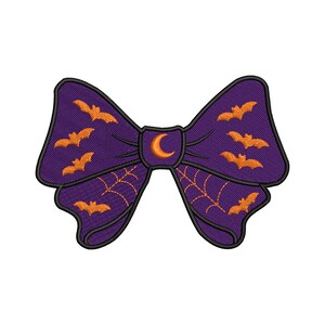 May include: A purple bow with orange bat and spiderweb designs, and a crescent moon in the center. The bow is a Halloween-themed accessory.