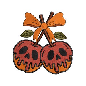 May include: Embroidered design of two red apples with skull faces, orange dripping edges, and brown stems. An orange bow and green leaves are above the apples. The design is on a white background.
