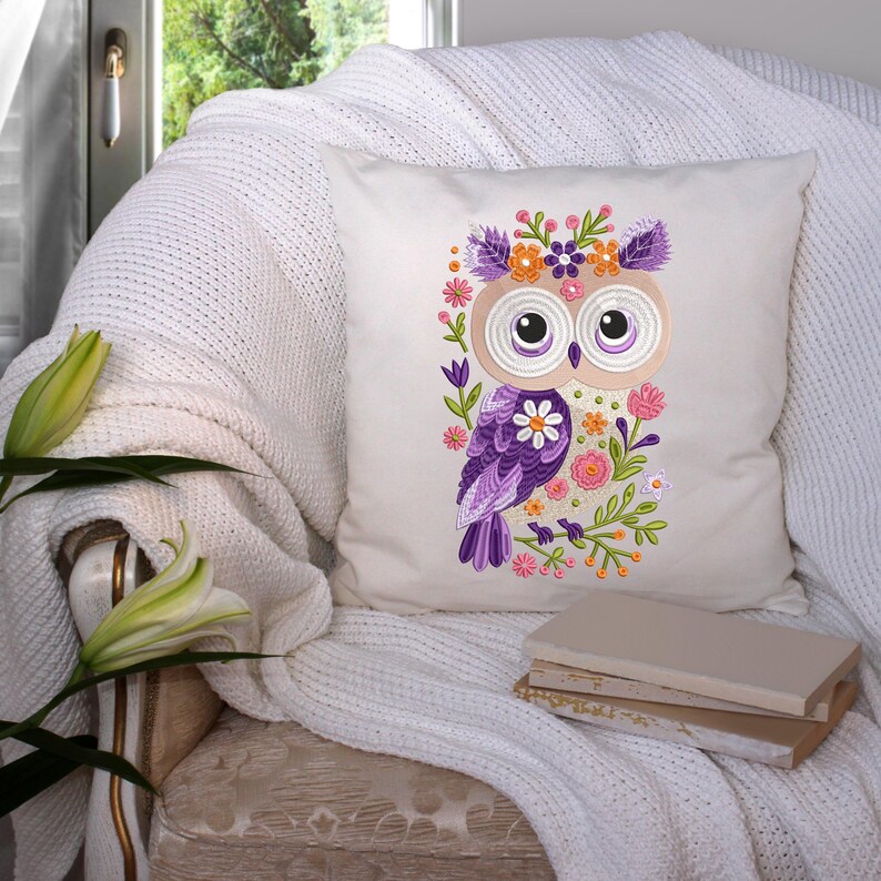 Peut inclure: Un oreiller blanc avec une chouette violette brod&eacute;e portant une couronne de fleurs. La chouette est entour&eacute;e de fleurs roses, violettes et vertes.