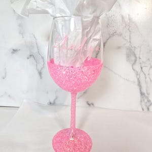 Bright pink glitter wine glass. Customized with person's name in pink vinyl.