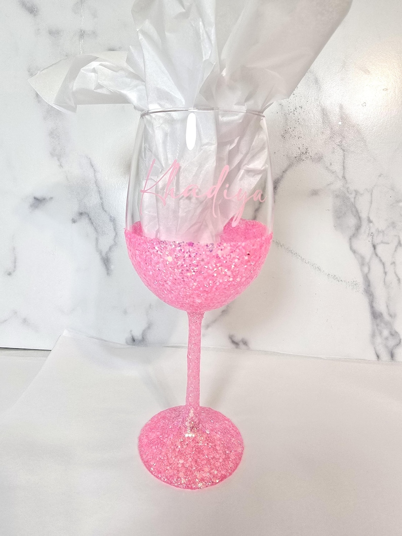 Bright pink glitter wine glass. Customized with person's name in pink vinyl.