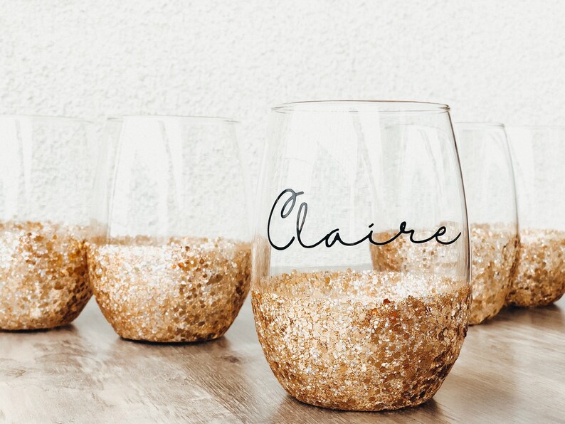 Chunky gold glitter wine glass with the Claire font. Black vinyl.
You can order the wine glass in a number of glitter colors and in your choice of font. Each glass is made to order.