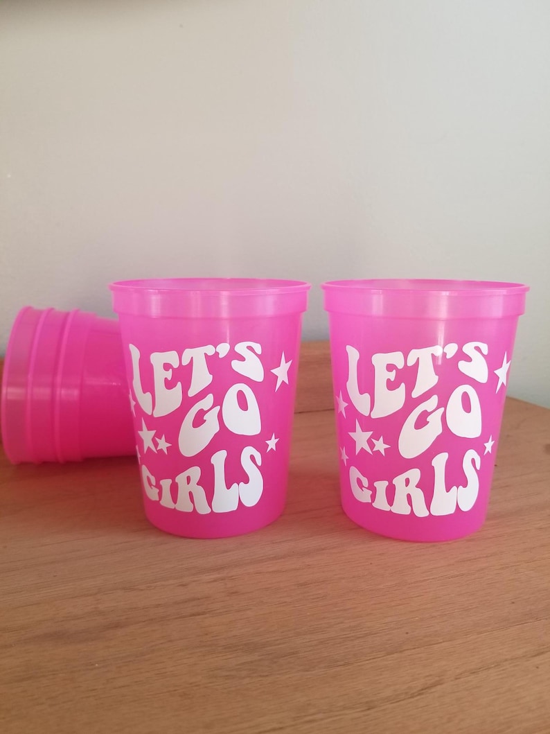 16 oz Stadium plastic cup that changes from Pink to Purple when ice cold drinks are added. White vinyl that says, "Let's Go Girls."
