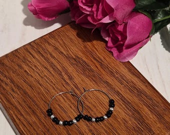 Pendientes de aro de plata hechos a mano con gancho, con una cuenta negra y un detalle de cuenta plateada.