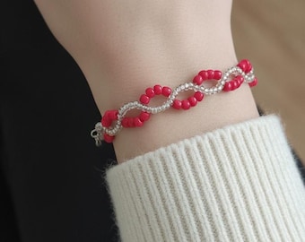 Pulsera de doble hebra con cuentas rojas y plateadas y cierre de mosquetón plateado.