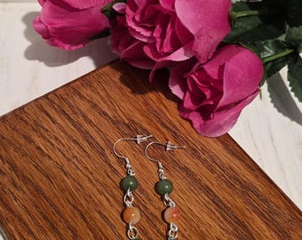 Pendientes colgantes hechos a mano con cuentas verdes y naranjas y detalles plateados.