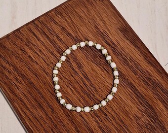 Pulsera elástica hecha a mano con cuentas doradas y blancas