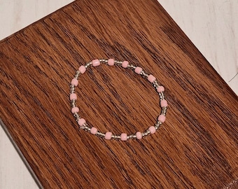 Preciosa pulsera elástica hecha a mano con cuentas de color rosa brillante y plata.