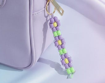 Llavero artesanal con cuentas de flores moradas y forma de poni.