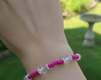 Pulsera de cuentas rosa oscuro con detalles de cuentas de flores plateadas, cuentas rosas transparentes y diseñada para ser elástica.