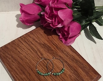 Pendientes de aro de plata hechos a mano con detalles de cuentas verdes y plateadas.