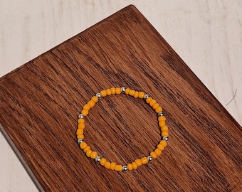 Pulsera elástica hecha a mano con cuentas de color naranja quemado y plata.