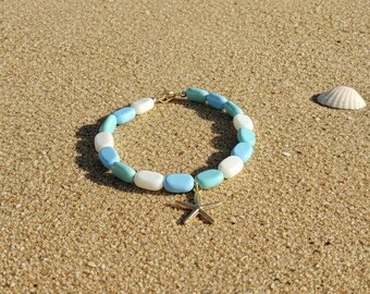 Hola, esta pulsera multicolor de Hello Beach en tonos azul, verde y crema con un dije de estrella de mar dorada es perfecta para tu estilo playero.