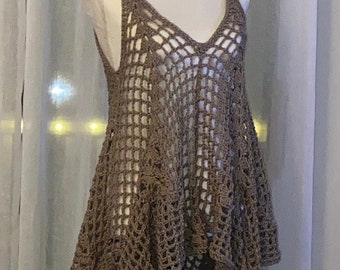May include: A brown, open-weave crochet top with a V-neck and spaghetti straps. The top has a loose, flowing design with a handkerchief hemline. The garment is displayed on a mannequin against a neutral background.