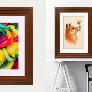 May include: Two dark brown wooden frames with white matting. The left frame displays a vibrant, multi-colored rainbow rose. The right frame features an illustration of an orange fox looking up at a small bee, presented in a room setting.