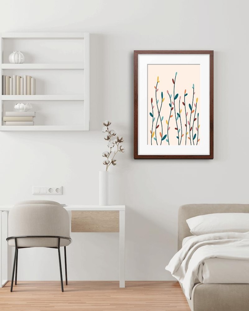 May include: A framed wall art print featuring a vertical botanical illustration of slender stems with small, multi-colored leaves in shades of teal, yellow, pink, and dark red against a pale cream background, enclosed in a dark brown wooden frame.
