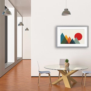 May include: A framed wall art print featuring a geometric mountain landscape with overlapping triangles in shades of teal, green, orange, and dark blue, set against a cream background with a large, solid red circle representing the sun.