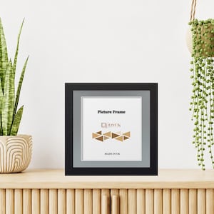 May include: A square black picture frame with a grey mat board. The insert features the text "Picture Frame", the "OSUK" logo, a graphic of brown and tan triangles, and the text "MADE IN UK" printed in black on a white background.