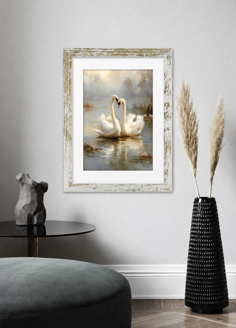 May include: A framed wall art print featuring two white swans swimming on a misty lake, their necks curved to form a heart shape. The artwork is enclosed in a rectangular, distressed white wooden frame with a white mat border.