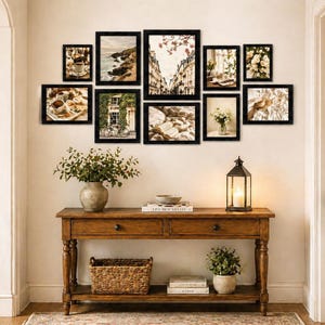 May include: A gallery wall arrangement featuring ten black rectangular frames containing various photographic prints, displayed above a wooden console table with two drawers, a lower shelf, a woven basket, and a decorative lantern.