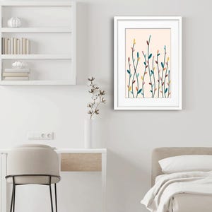 May include: A framed wall art print featuring a light peach background with a series of thin, vertical black stems adorned with small, colorful oval leaves in shades of teal, yellow, pink, and dark red, displayed in a white frame.