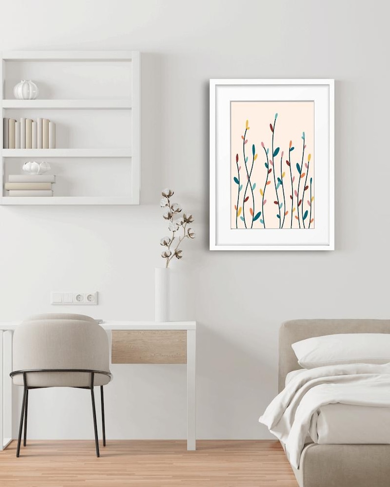 May include: A framed wall art print featuring a light peach background with a series of thin, vertical black stems adorned with small, colorful oval leaves in shades of teal, yellow, pink, and dark red, displayed in a white frame.