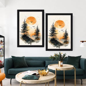 Peut inclure: Deux cadres muraux repr&eacute;sentant des paysages &agrave; l'aquarelle avec des silhouettes noires de pins et d'oiseaux devant un grand soleil orange. L'&oelig;uvre utilise une palette de tons orange, noir et cr&egrave;me, pr&eacute;sent&eacute;e dans des cadres noirs assortis.