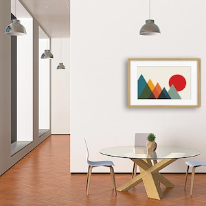 May include: A framed wall art print featuring a geometric mountain landscape with overlapping triangles in shades of teal, orange, dark blue, and olive green, set against a cream background with a large solid red circle representing the sun.
