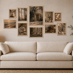 May include: A gallery wall of framed art prints depicting tranquil scenes, including a beach at sunset, a window with curtains, and a cosy interior. The prints are arranged above a cream sofa, creating a warm and inviting atmosphere in the room.