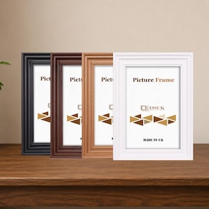 May include: Four rectangular picture frames in black, dark brown, light wood grain, and white finishes. Each frame features a stepped border design and contains a white insert with the text Picture Frame, the OSUK logo, and MADE IN UK.