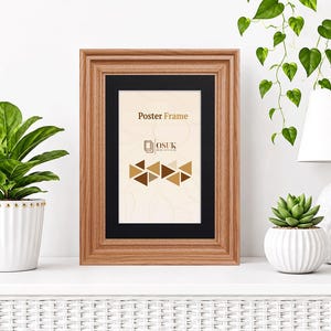 May include: A rectangular wooden poster frame with a black mount. The insert features the text "Poster Frame" and "OSUK" above a pattern of brown and tan triangles. The frame has a light brown wood grain finish and a classic stepped profile.