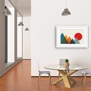 May include: A framed wall art print featuring a geometric mountain landscape with overlapping triangles in shades of teal, green, orange, and dark blue, set against a cream background with a large solid red circle representing the sun.