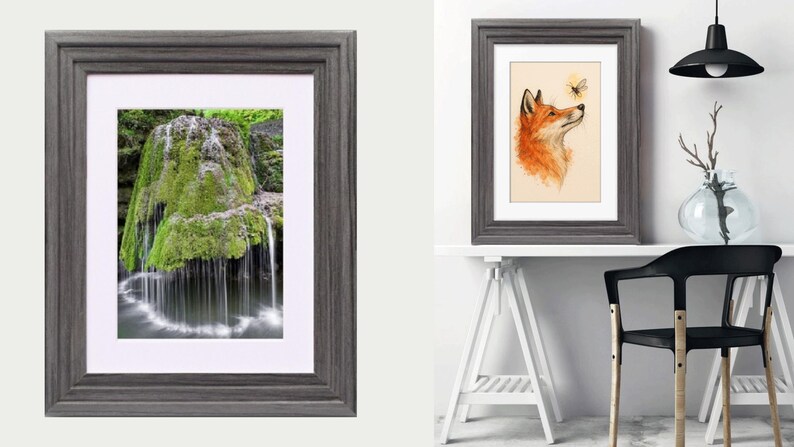 May include: A dark gray wooden picture frame with a white mat board. The frame features a stepped profile and holds a vertical rectangular print of a moss-covered rock formation with water cascading down into a pool at the base of the structure.