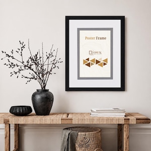 May include: A black rectangular poster frame with a white mount and a grey inner border. The frame contains a display sheet with the text Poster Frame, the logo OSUK, and a graphic pattern of brown and gold triangles on a light background.