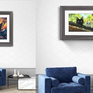 May include: Two framed wall art prints displayed in a room. The left print features a bald eagle flying over dark mountains at sunset. The right print shows a black cat and a white cat peering over a wooden roof edge amidst green foliage.