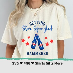Puede incluir: Una camiseta blanca con el texto "Getting Star Spangled Hammered" en azul y rojo. El diseño presenta dos botellas de cerveza azules con estrellas rojas alrededor.