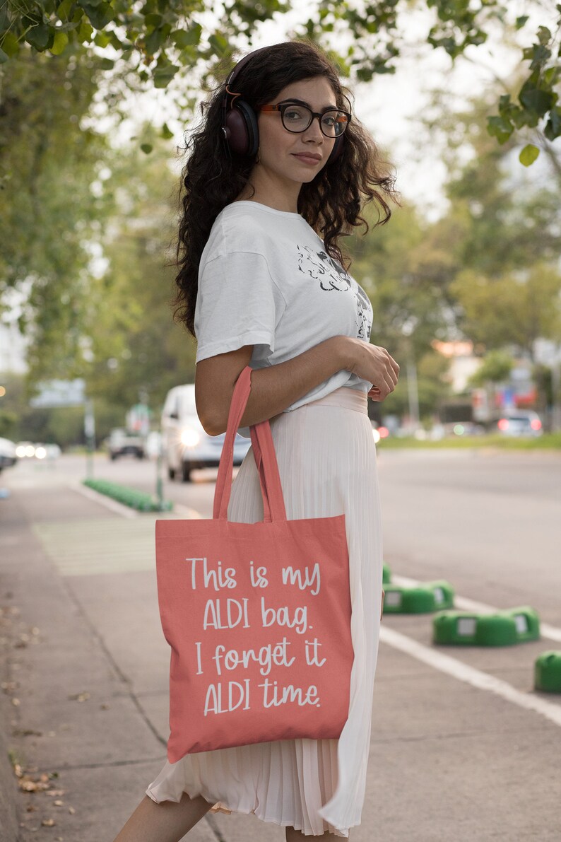 Op de afbeelding: Een koraalkleurige tote bag met witte tekst die "This is my ALDI bag. I forget it ALDI time." zegt.