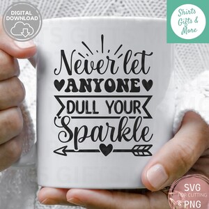 Op de afbeelding: Een witte keramische mok met zwarte tekst die "Laat nooit iemand je glans dimmen" zegt met een hart en pijl grafiek.