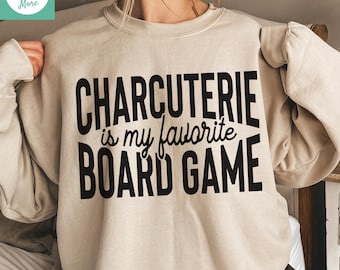 May include: A beige sweatshirt featuring the black text "CHARCUTERIE is my favourite BOARD GAME". The long-sleeved top has a crew neck. The image also includes the text "Shirts Gifts & More" and "Digital Download: SVG • PNG • DXF • EPS".